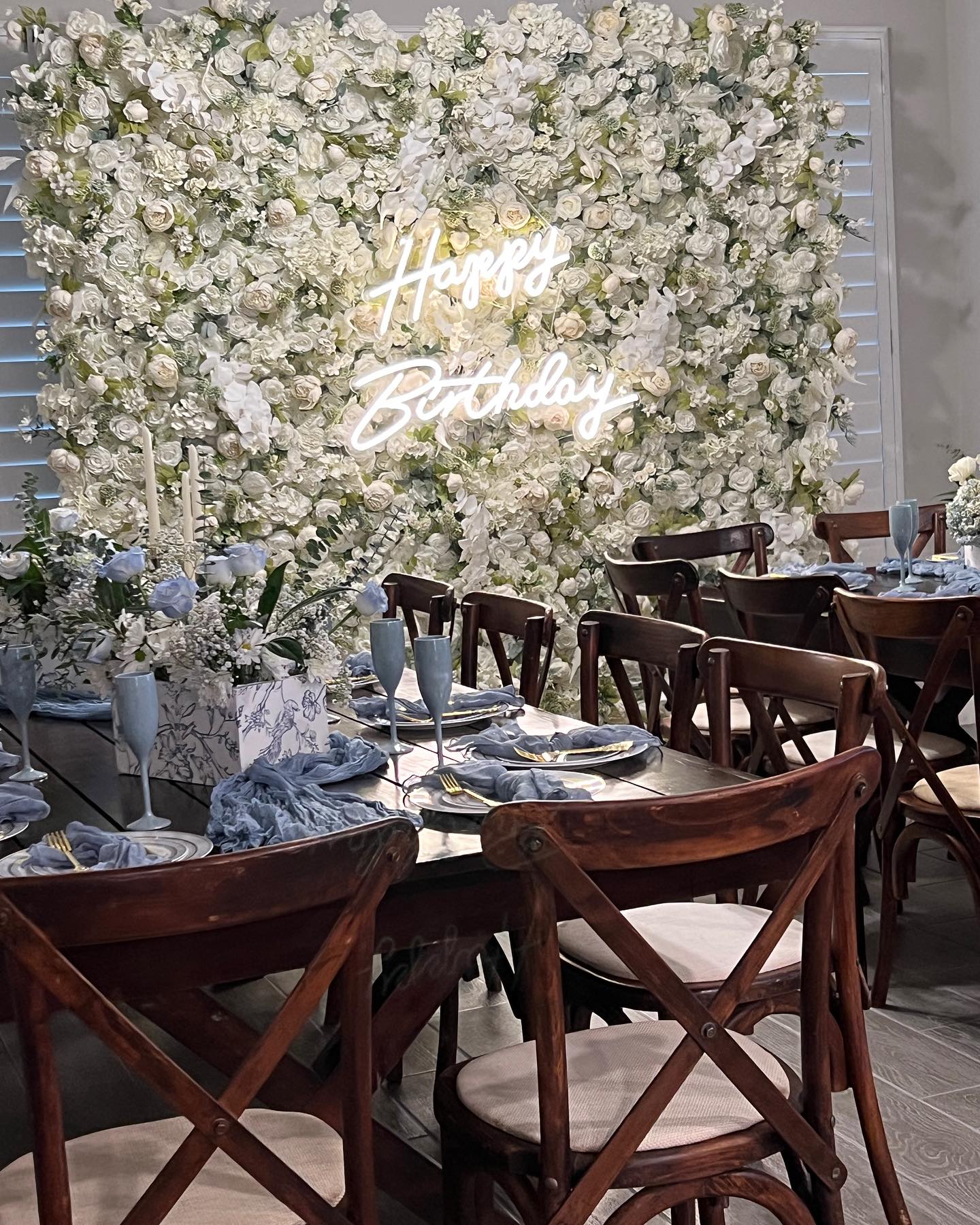 Elegant birthday celebration setup featuring a flower wall and a glowing "Happy Birthday" sign