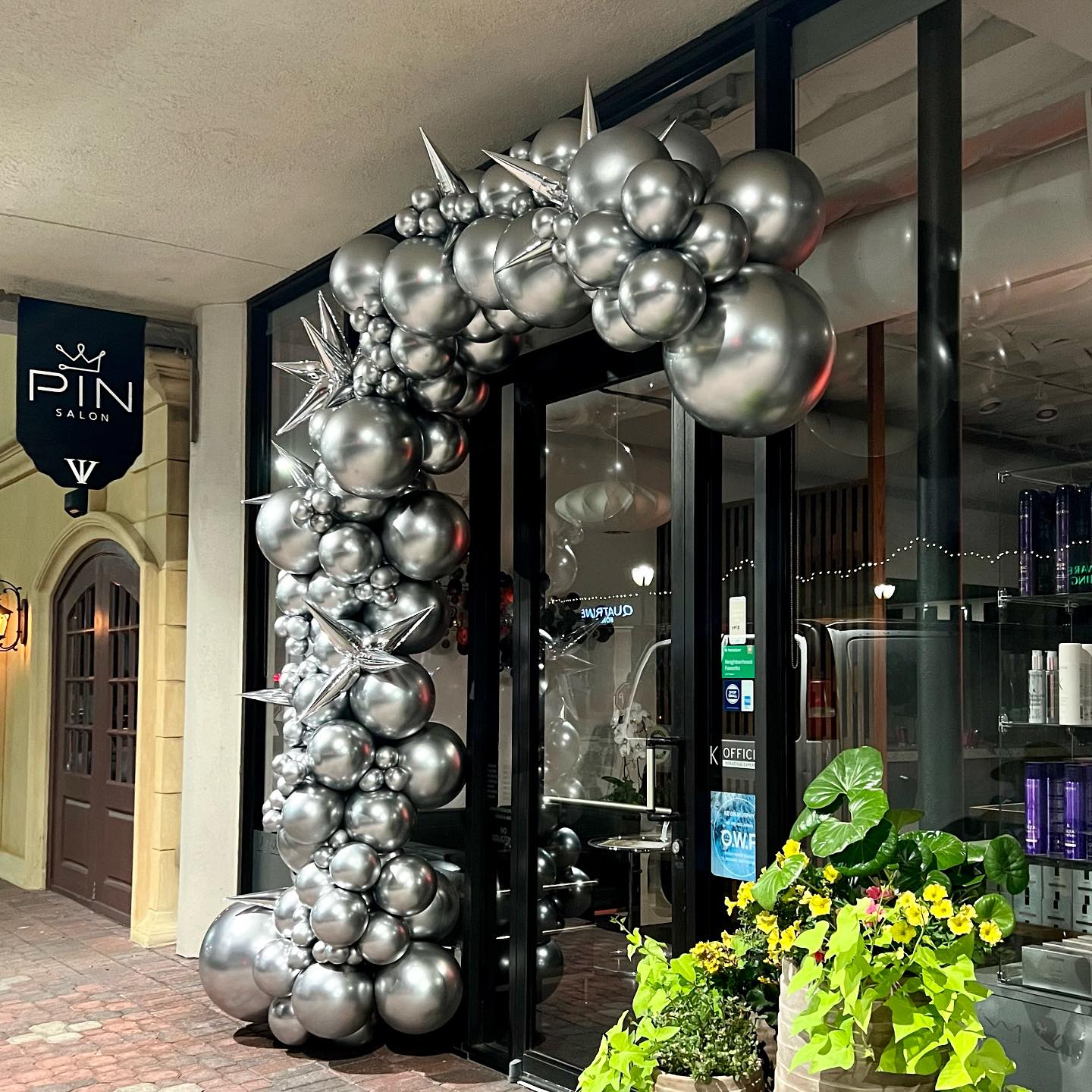 Silver balloon arch with star accents adorns the entrance of PIN Salon, inviting customers into the stylish interior.