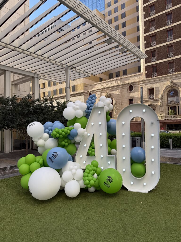 A festive display featuring large, illuminated numbers "40" surrounded by colorful balloons in green, blue, and white, celebrating a milestone event.