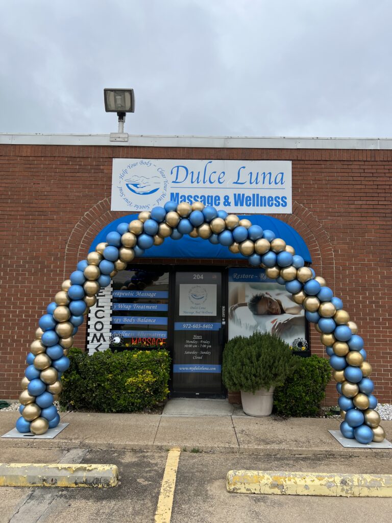 Colorful balloon arch marking the entrance of Dulce Luna Massage & Wellness. The storefront features wellness services and inviting signage.