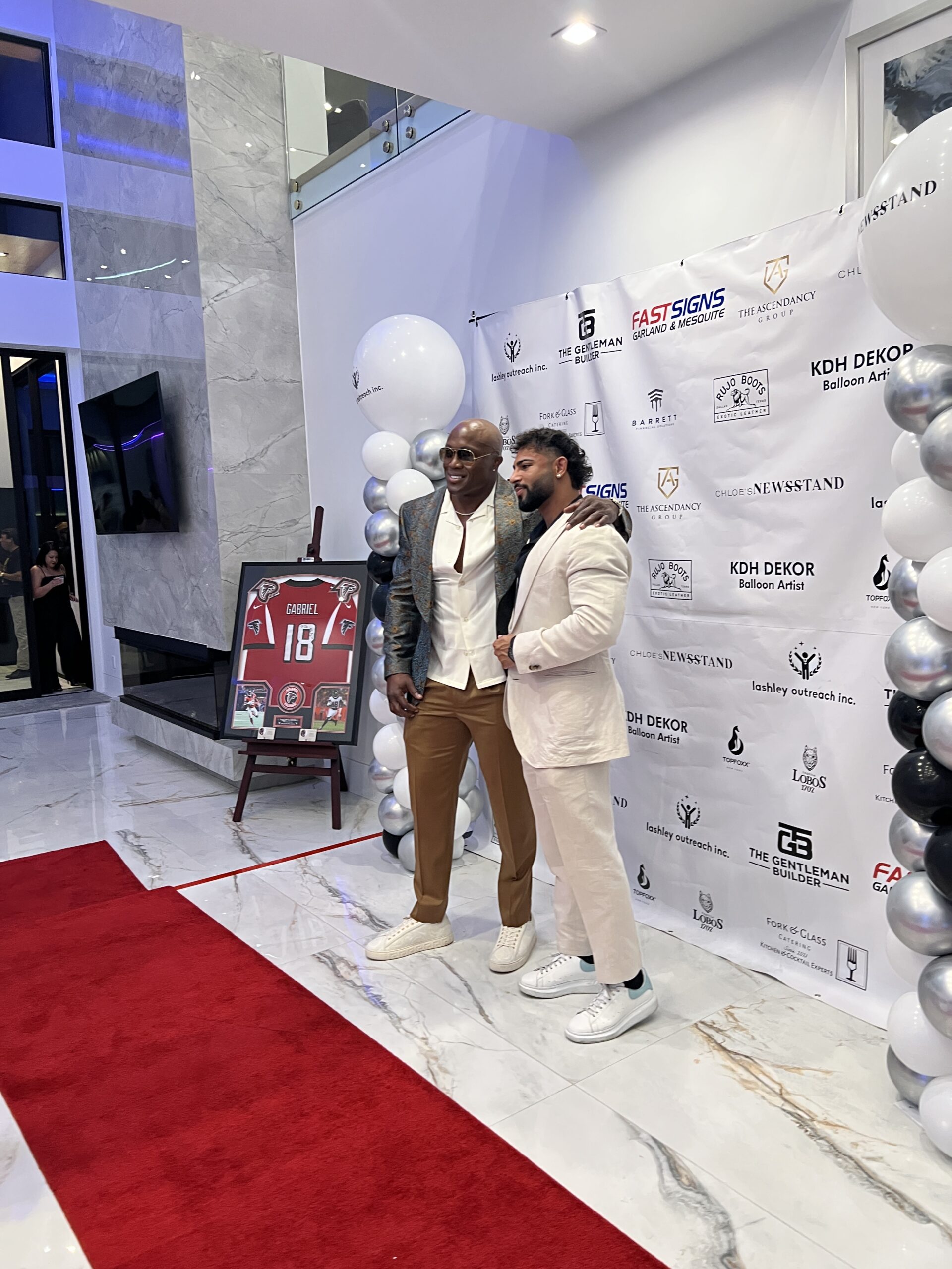 Two men pose for a photo in stylish outfits at a glamorous event